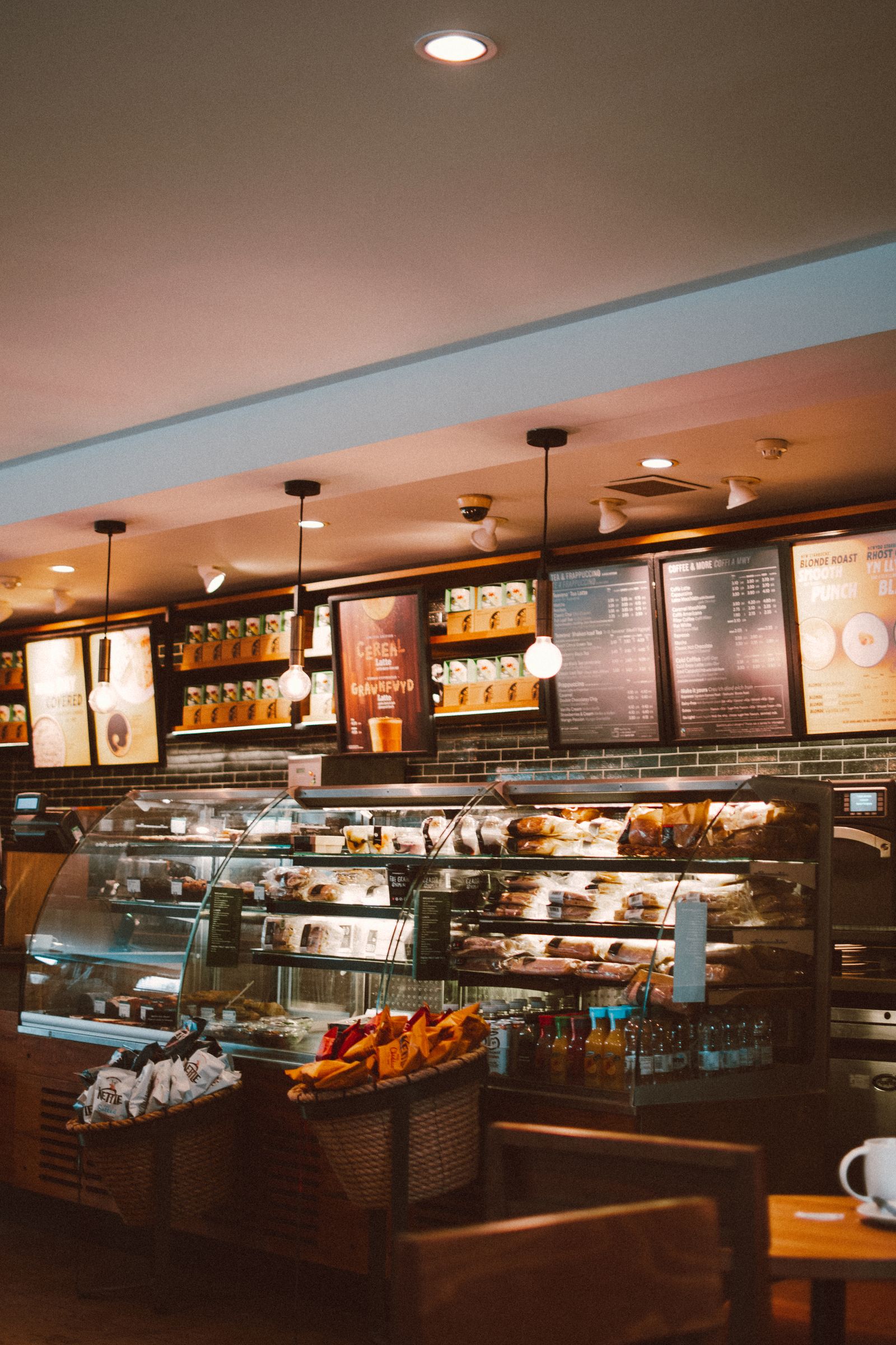 Warmly lit counter of Demlik cafe with timber shelving and pastry displays