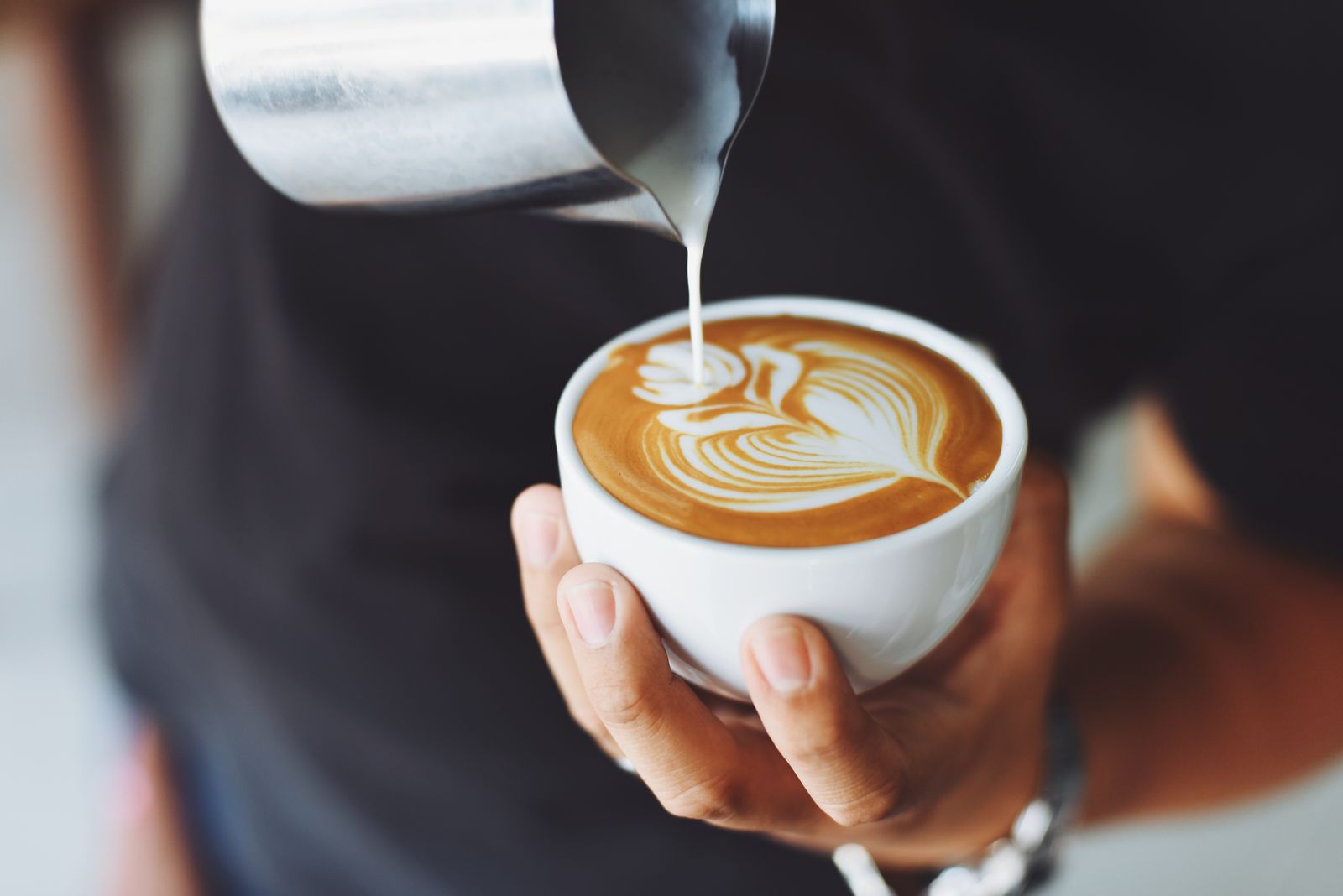 Steamed milk being poured slowly into a ceramic cup at the end of the meal
